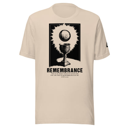 A beige crewneck T-shirt featuring a black graphic print of The Catholic Eucharist with the word 'REMEMBRANCE' and smaller text of the bible verse Luke 22:19. Catholic Clothing.